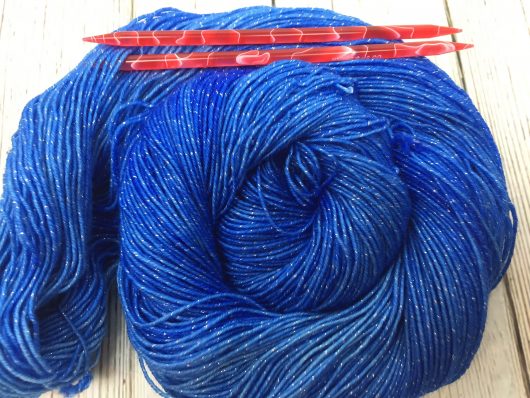 blue yarn with metallic flecks with red needles