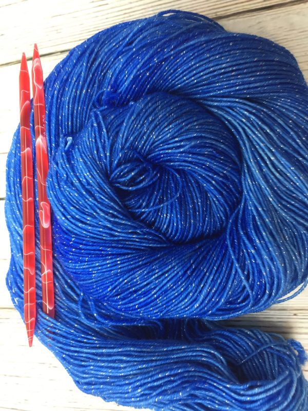 blue yarn with metallic flecks with red needles