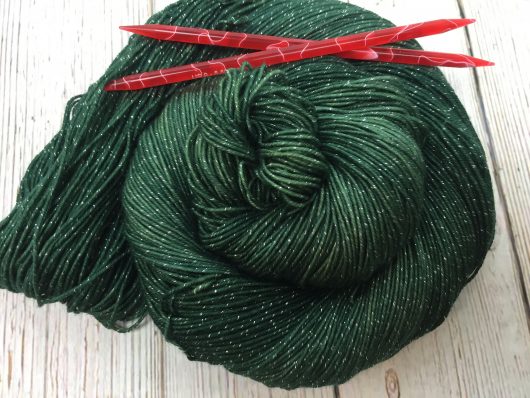 forest green yarn with metallic flecks with red needles