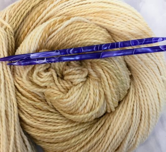 soft yellow cream marled yarn with blue needles