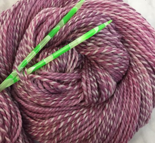 red violet marled yarn with green needles