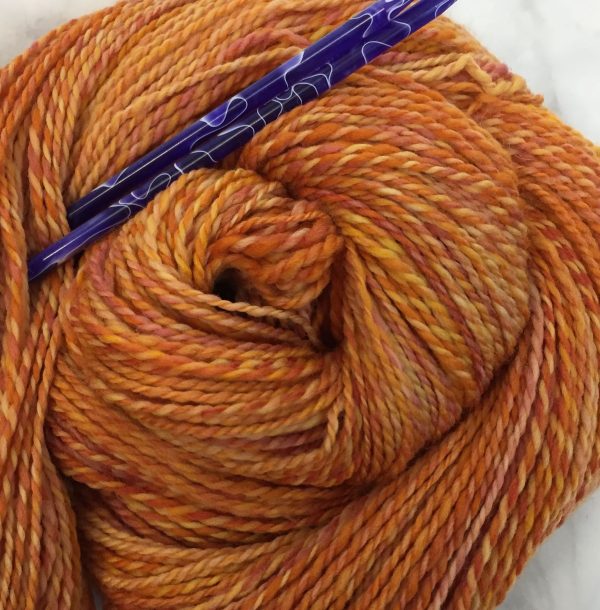 orange and yellow marled yarn with blue needles