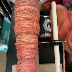 spindle of yarn in oranges and pinks