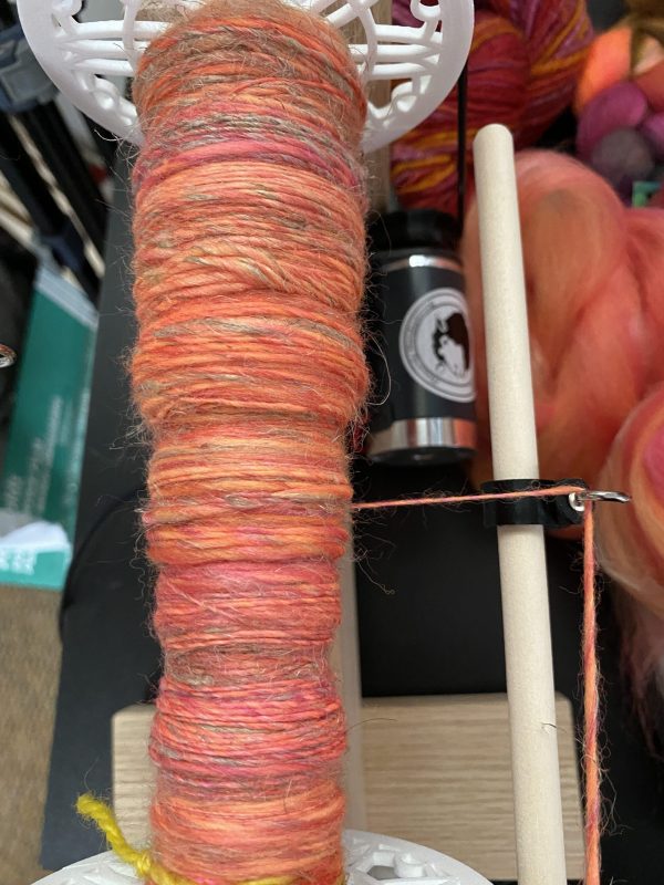 spindle of yarn in oranges and pinks